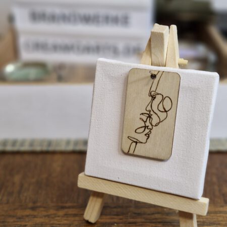 Holz-Schlüsselanhänger mit One-Line-Motiv: Mann küsst Frau auf die Stirn