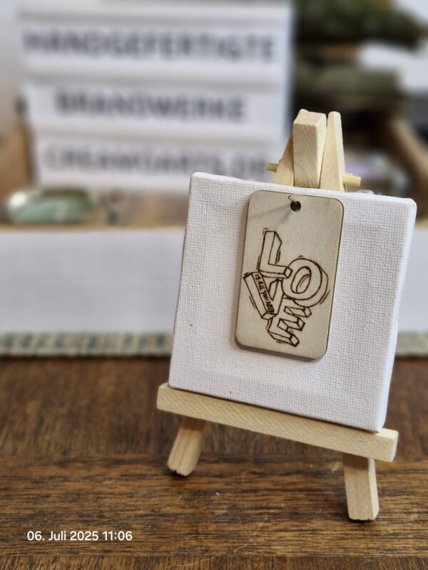 Handgebrannter Holz-Schlüsselanhänger mit dem Schriftzug LOVE und Herzkarabiner auf hellem Untergrund