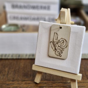 Handgebrannter Holz-Schlüsselanhänger mit dem Schriftzug LOVE und Herzkarabiner auf hellem Untergrund